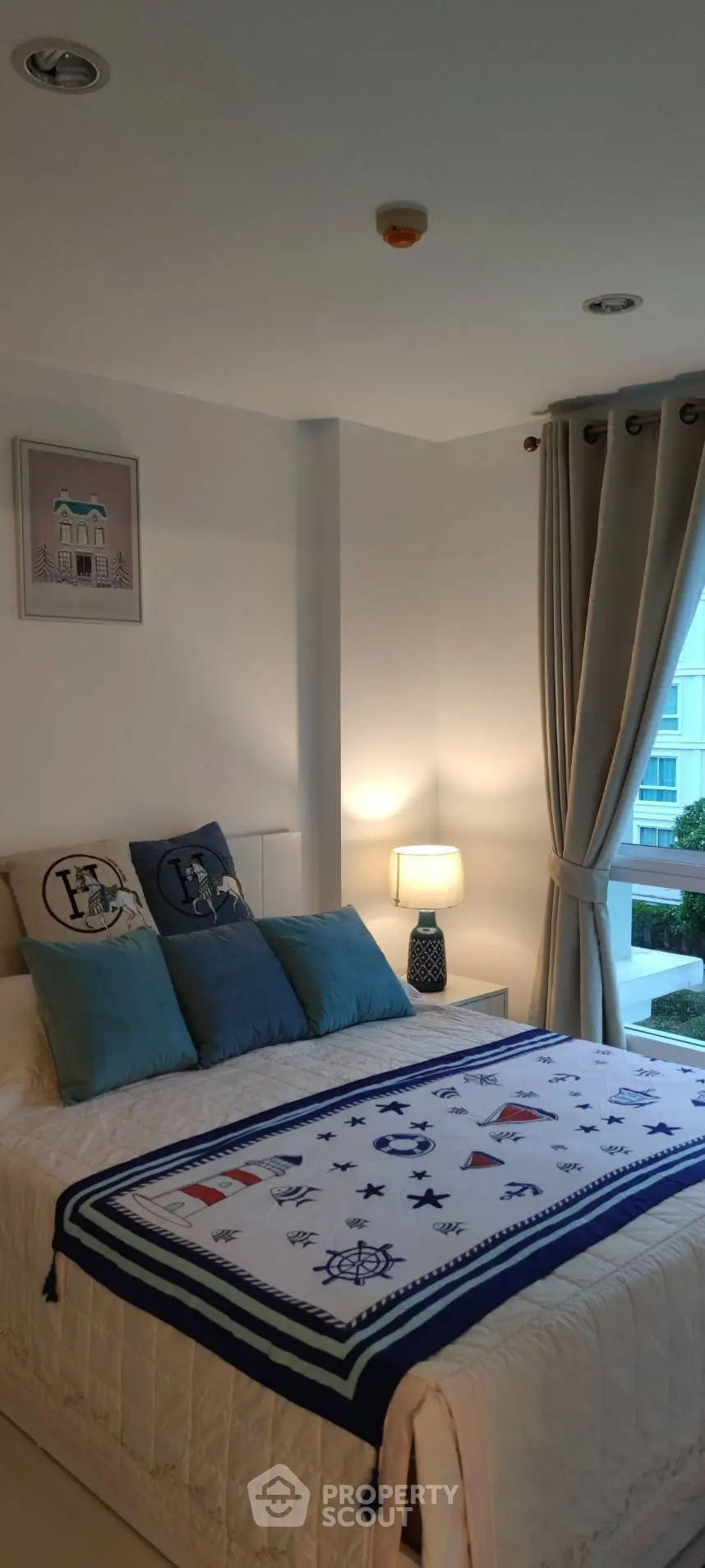 Cozy bedroom with nautical-themed decor and large window view, perfect for relaxation.