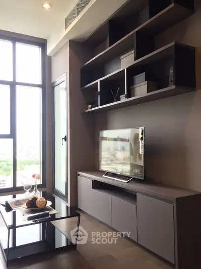 Modern living room with sleek TV unit and large window offering natural light.