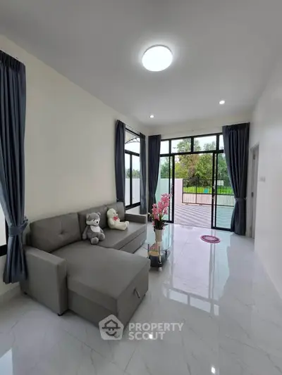 Spacious living room with modern decor and large windows offering a serene garden view.