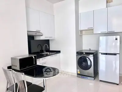 Sleek modern kitchen with high-end appliances, including a Samsung fridge and washing machine, complemented by white cabinetry and a cozy dining nook.