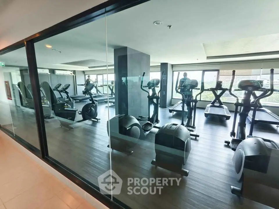 Modern gym with state-of-the-art equipment and large windows offering a bright and airy workout space.