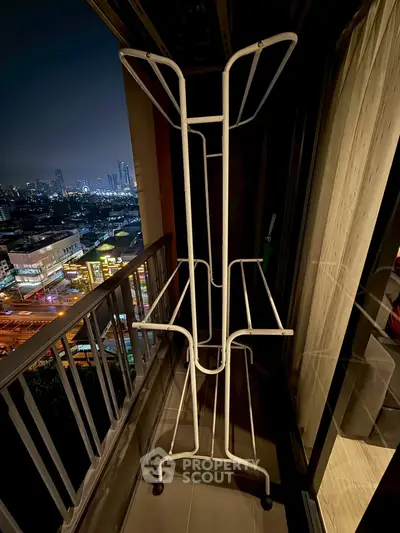 City view from high-rise balcony with drying rack at night