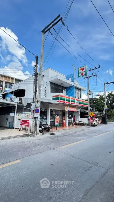 Street view of a commercial building with a convenience store and clear blue sky.