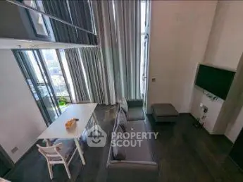 Modern living room with high ceilings and large windows offering stunning city views.