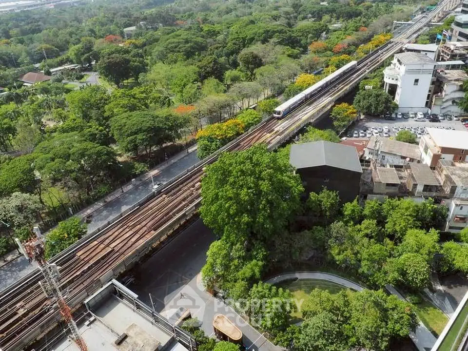 Aerial view of lush green urban landscape with railway and residential buildings.