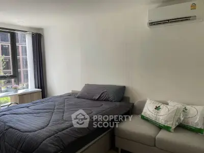 Modern bedroom with cozy bed, air conditioning, and natural light from large window.