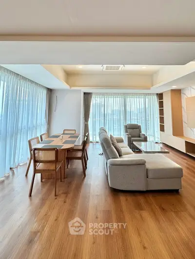 Spacious modern living room with elegant dining area and floor-to-ceiling windows.