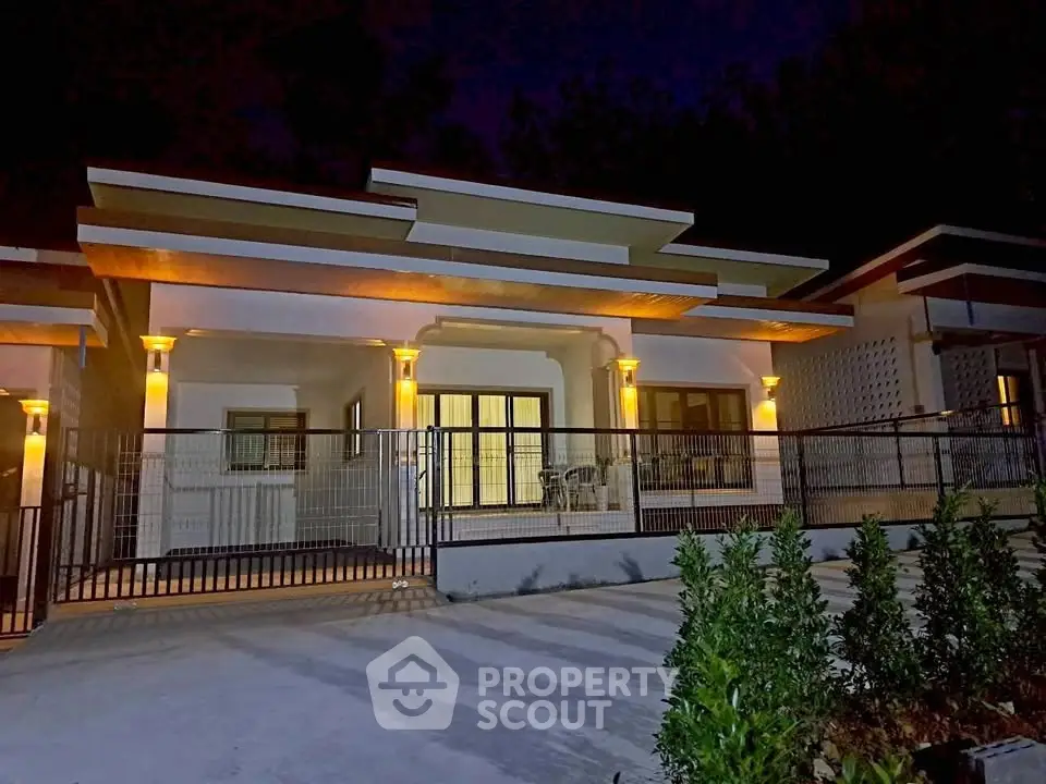 Charming single-story home with modern lighting and spacious front patio, perfect for evening relaxation.