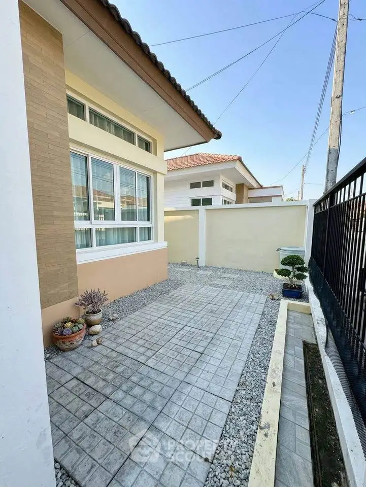 Charming exterior view of a modern house with a neat gravel pathway and potted plants.