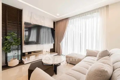 Luxurious modern living room with plush sofa and large TV, featuring elegant decor and natural light.