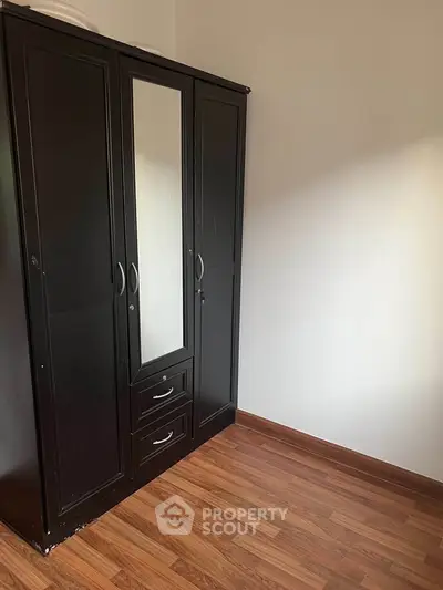 Spacious bedroom with elegant dark wardrobe and wooden flooring