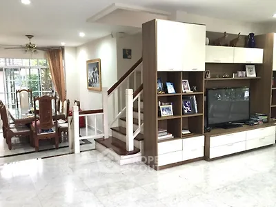 Spacious living room with elegant dining area and modern staircase in a stylish home.
