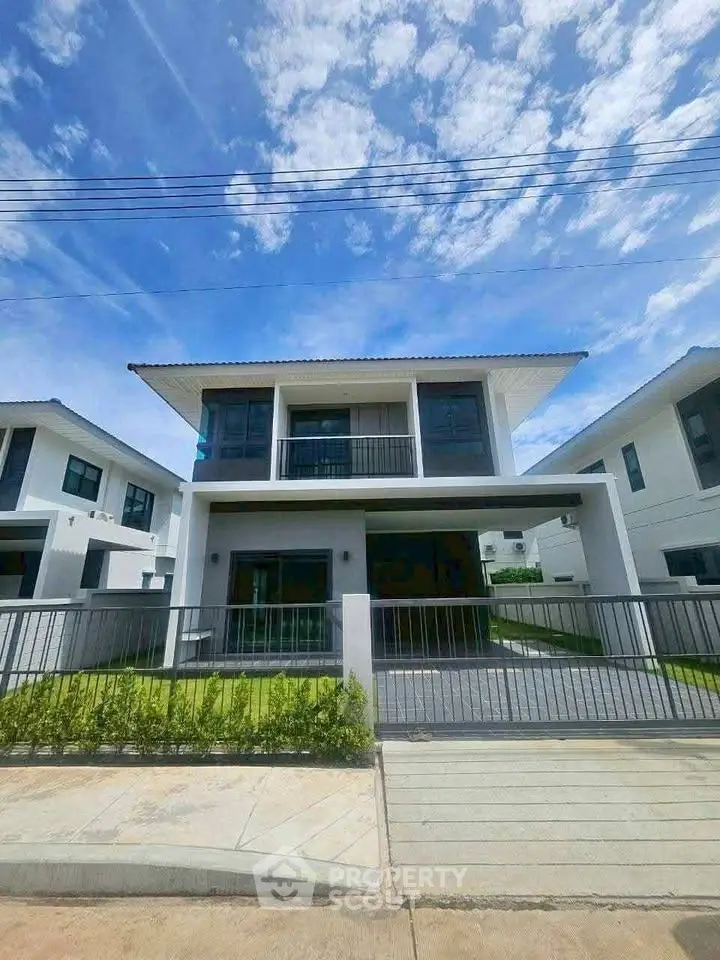 Modern two-story house with balcony and driveway in a serene neighborhood.