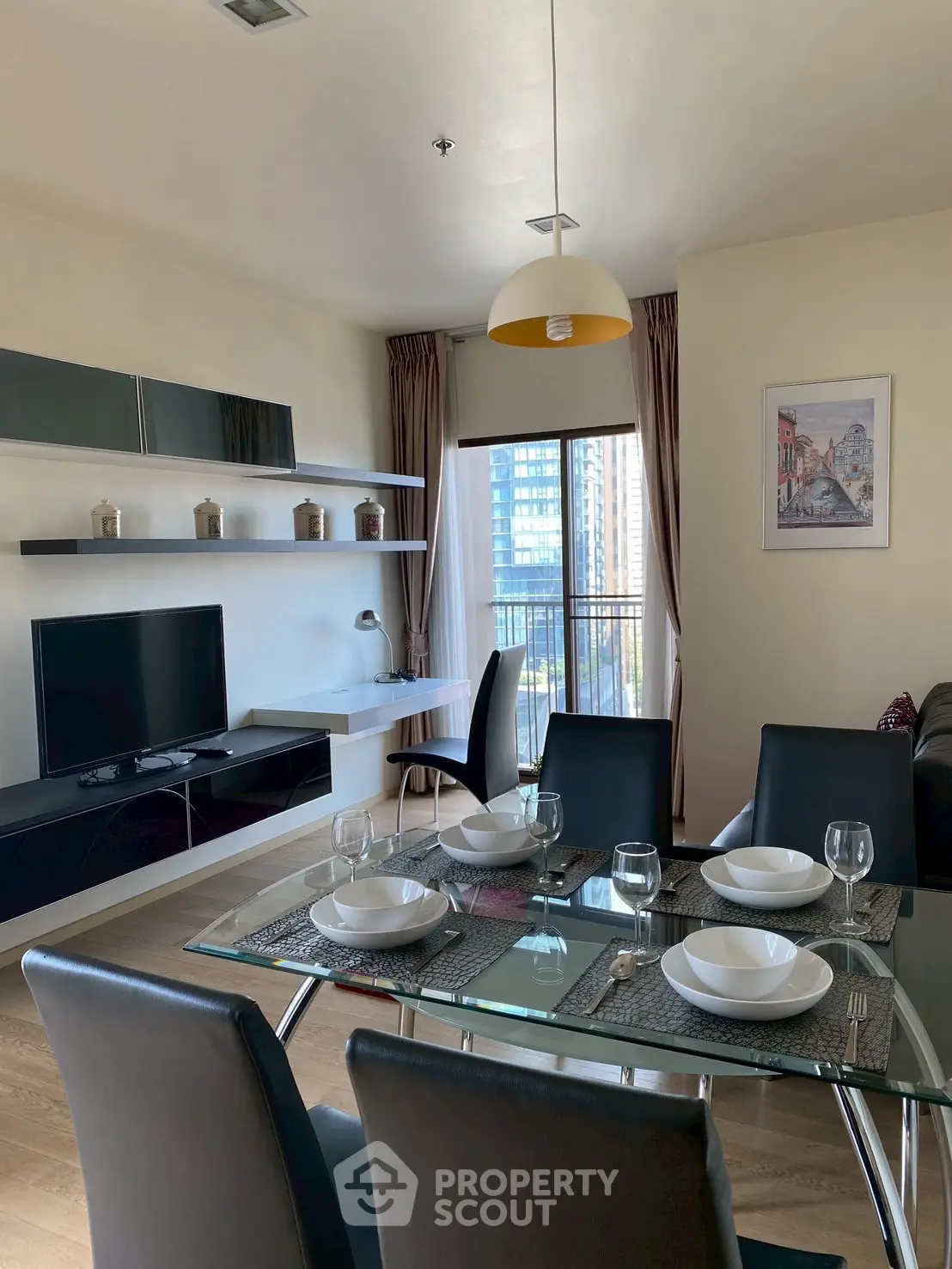 Modern dining area with glass table and city view from balcony in stylish apartment.