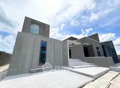 Modern minimalist concrete house exterior with large windows and clean lines under a bright blue sky.