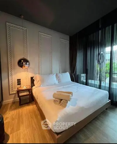 Luxurious bedroom with modern decor and large window offering natural light and garden view.