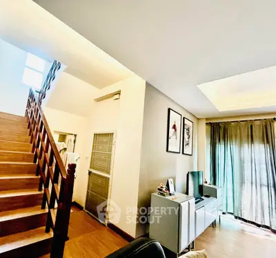 Spacious living room with modern decor and natural light, featuring a stylish staircase and elegant furnishings.