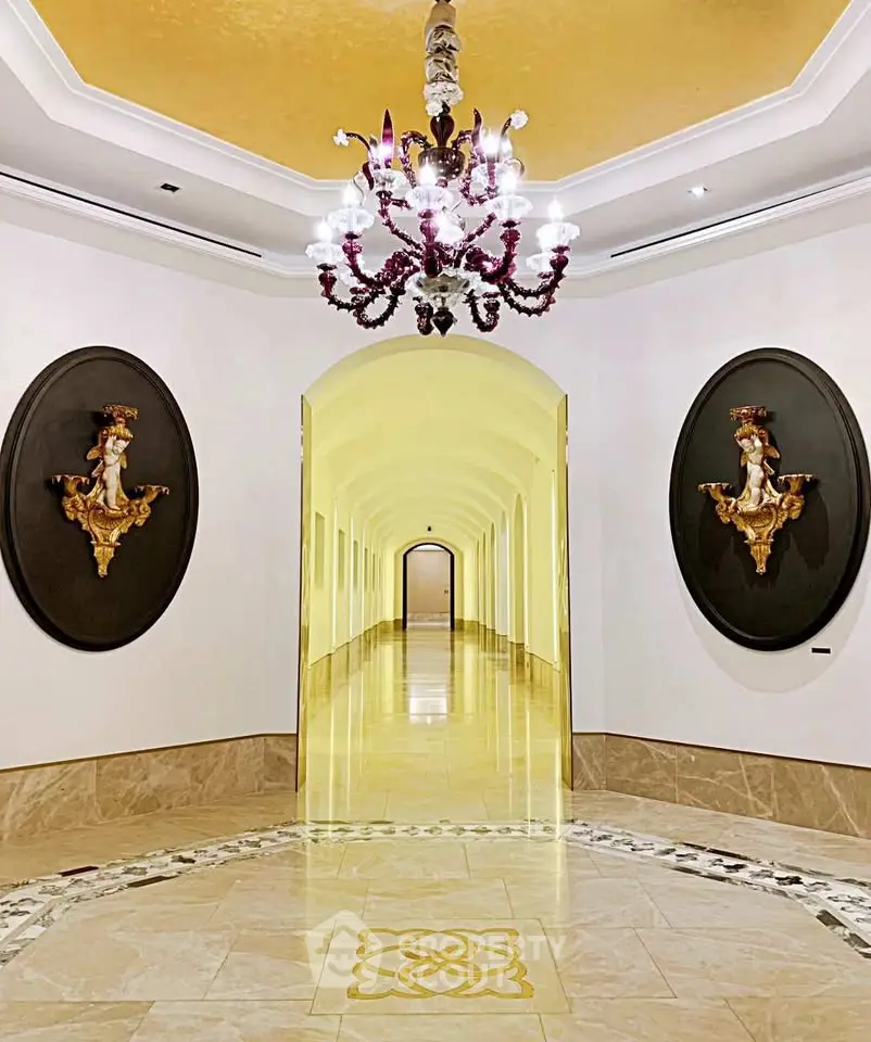 Luxurious hallway with ornate chandelier and elegant wall decor in upscale building.