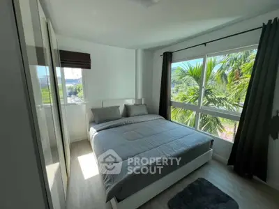 Bright bedroom with large windows and lush greenery view