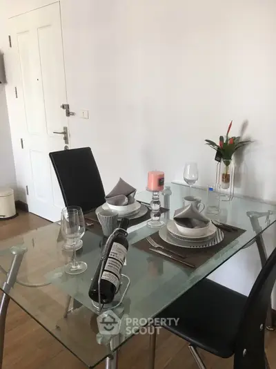 Modern dining area with glass table and elegant place settings in a stylish apartment.