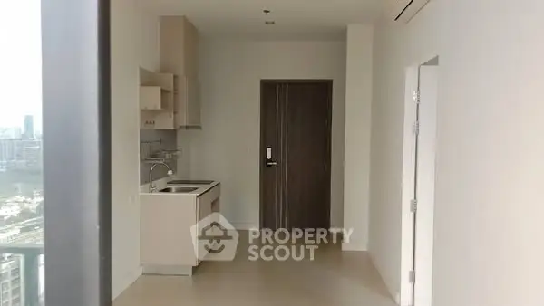 Modern minimalist apartment interior with compact kitchen and city view.