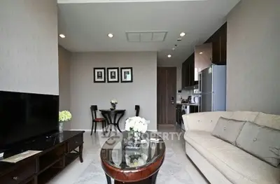 Modern living room with elegant decor and open kitchen layout, featuring a cozy sofa and stylish dining area.