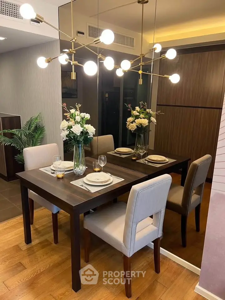 Elegant dining area with modern chandelier and wooden table set for four, featuring stylish decor and warm lighting.
