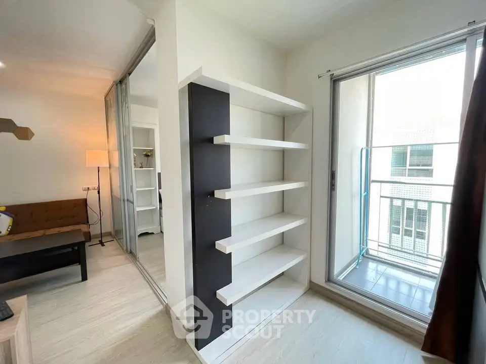 Modern living room with sleek shelving and balcony access in a stylish apartment.
