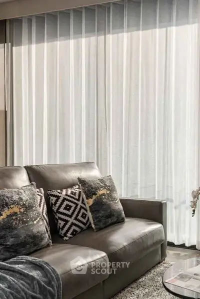 Modern living room with stylish sofa and decorative pillows, featuring floor-to-ceiling curtains.