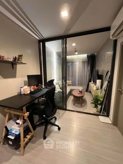 Modern study room with glass partition and cozy living area in stylish apartment.