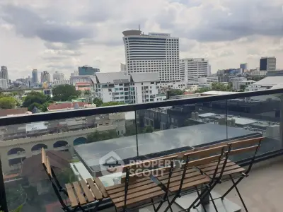 Stunning cityscape view from a modern balcony with sleek glass railing and stylish outdoor furniture.