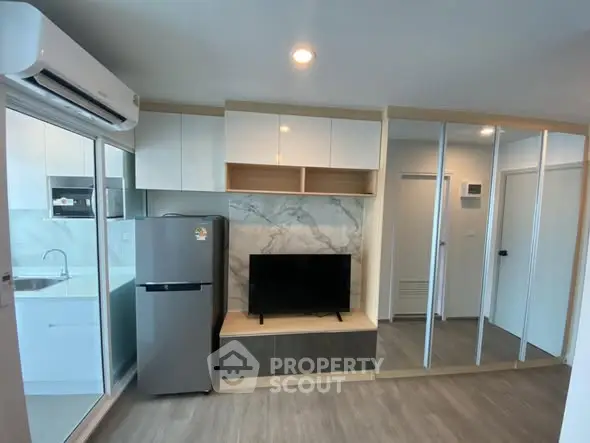 Modern living room with sleek design, featuring a TV, fridge, and mirrored storage.