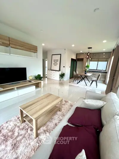 Modern living room with stylish decor and open dining area, featuring sleek furniture and natural light.