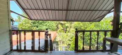 Charming balcony with lush garden view and rustic wooden railing, perfect for relaxation.