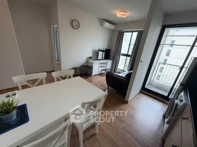 Modern apartment living room with dining area and balcony access, featuring sleek furniture and natural light.