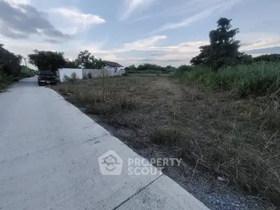 Vacant land plot with potential for development, featuring lush greenery and a clear sky backdrop.