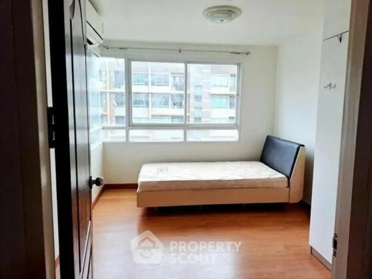 Bright bedroom with large window and single bed in modern apartment.