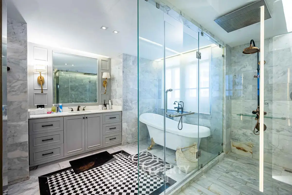 Luxurious bathroom with freestanding tub and glass shower in elegant marble setting.