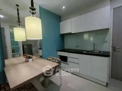 Modern kitchen with sleek cabinetry and dining area featuring stylish pendant lights.