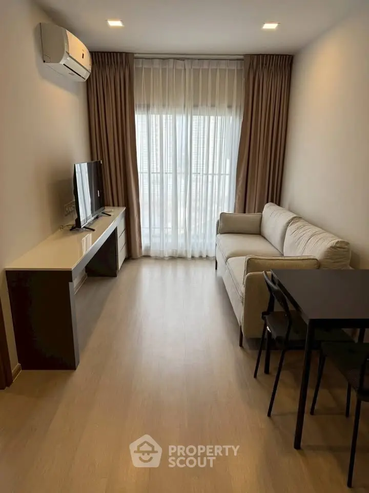 Modern living room with natural light, cozy sofa, and sleek TV setup in a stylish apartment.