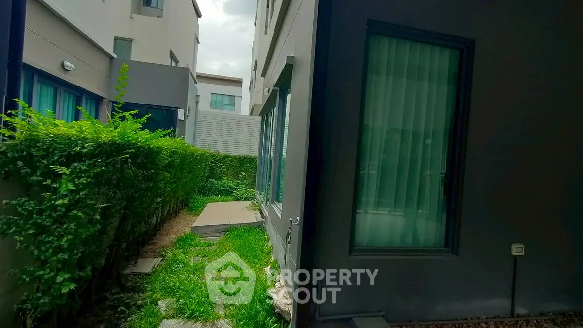 Modern townhouse exterior with lush green garden and large windows