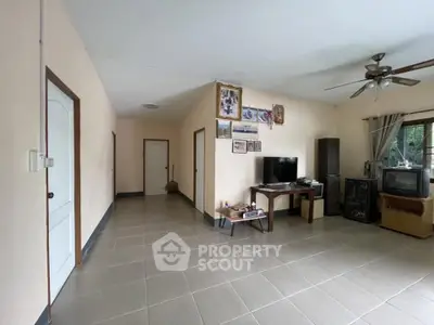 Spacious living room with tiled floor, ceiling fan, and natural light, perfect for family gatherings.