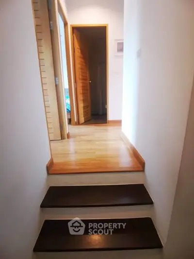Charming hallway with wooden steps leading to cozy rooms, perfect for a modern home.