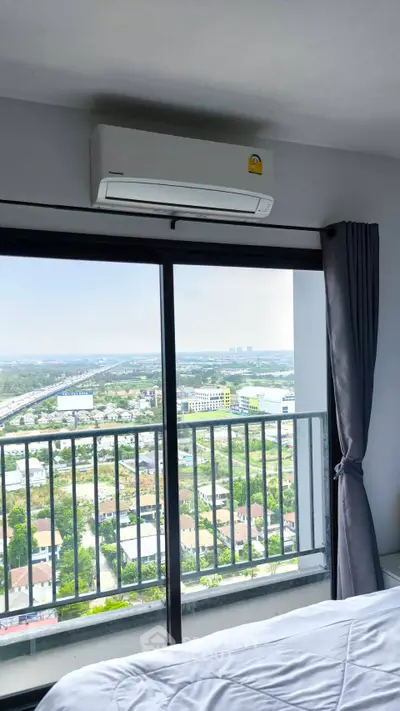 Modern bedroom with stunning city view from large window and air conditioning unit.