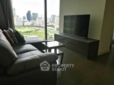 Modern living room with city view, featuring sleek furniture and large TV.