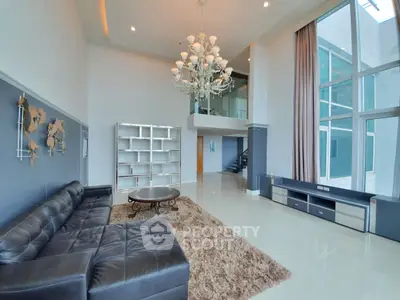 Luxurious modern living room with high ceilings, elegant chandelier, and large windows for natural light.