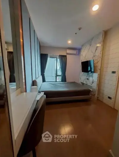 Modern bedroom with stylish decor and large window offering natural light.