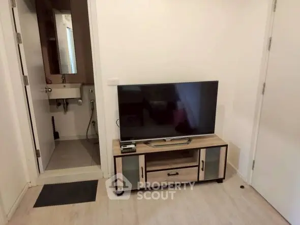 Cozy living room with modern TV setup and adjacent bathroom in a compact apartment.