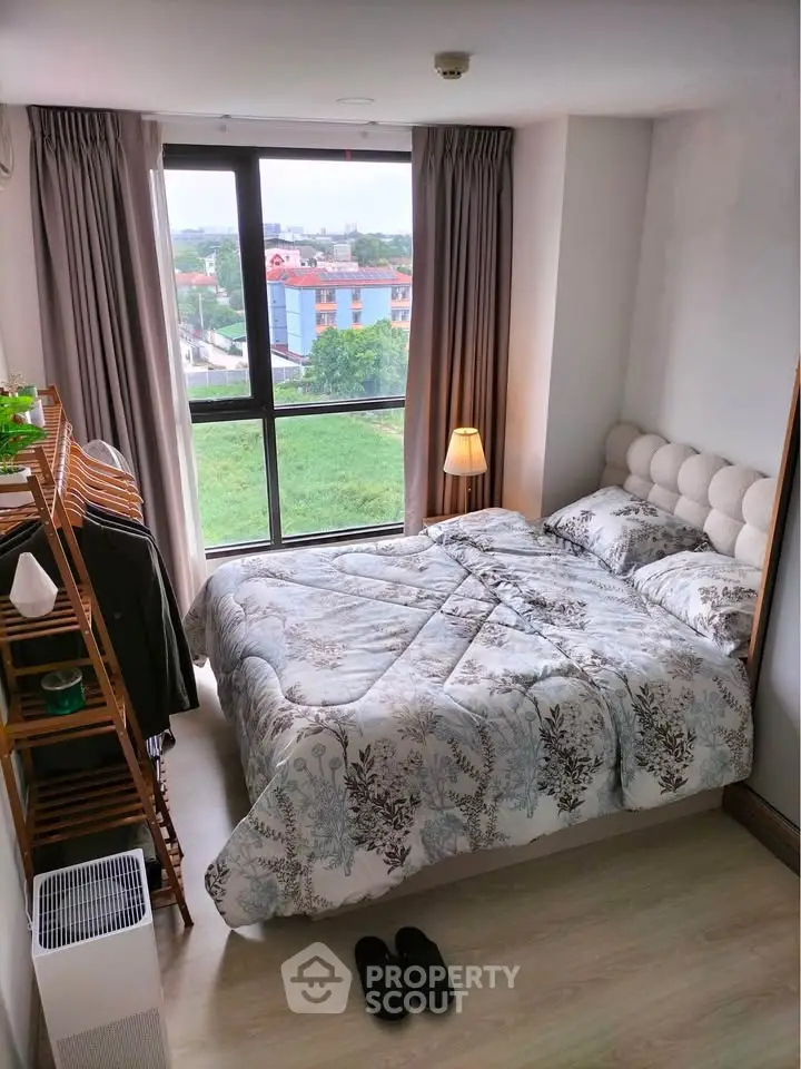 Cozy bedroom with large window offering scenic views, featuring stylish decor and comfortable bedding.
