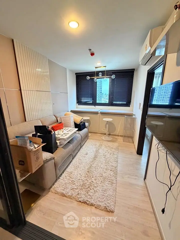 Modern living room with cozy sofa, stylish decor, and large window offering natural light.